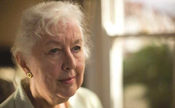 An older woman stands by a window
