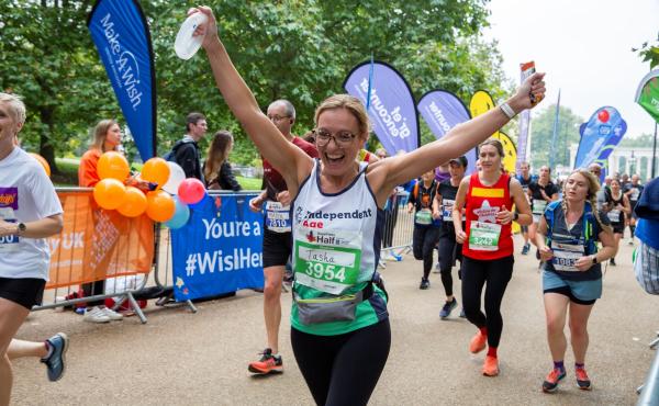 Woman smiling with her arms up as she reaches the finish line of a running race